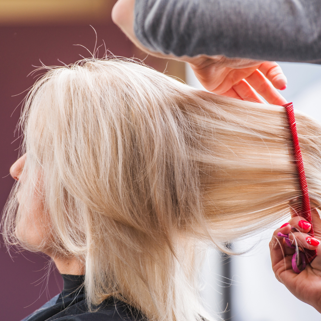 Stylist combing blonde hair during a precision cut